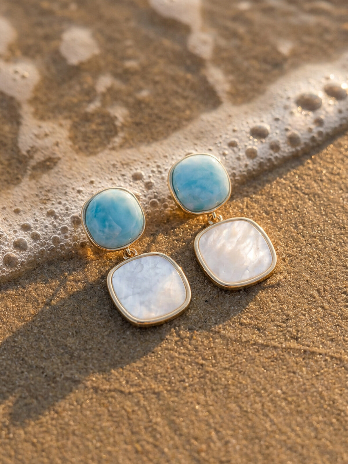 Larimar and mother-of-pearl earrings, photographed on the beach